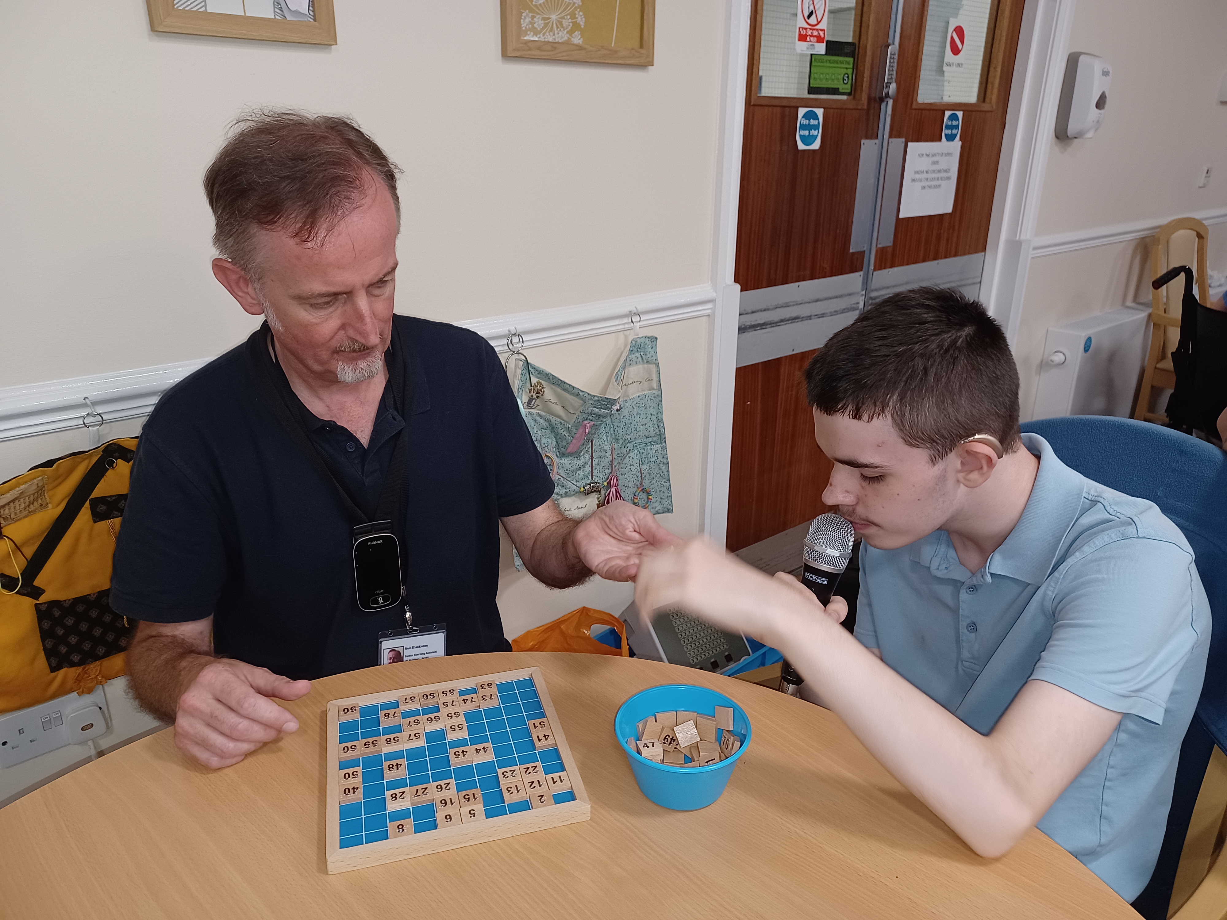 A man and a teenage boy.  the teenage boy has a microphone in his hand and is calling bingo numbers