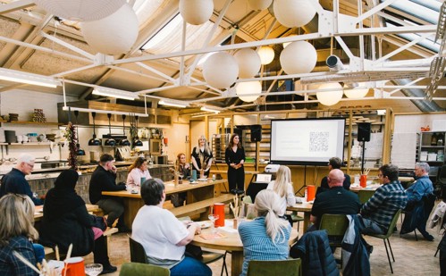 Large room with people at tables watching some at the front give a speech